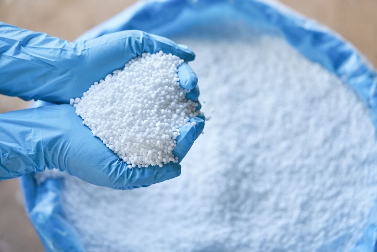 Gloved hands holding urea granules